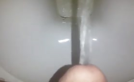 Stroking his cock while peeing in the toilet