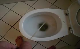 Mature man stroking his cock while peeing in the toilet