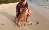 Squatting on beach sand, vulva visible