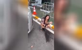 Asian woman squats on curb and pisses on road